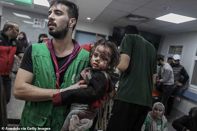 An injured young child is carried by an apparent medic after an airstrike on Al-Ahli Baptist Hospital in Gaza City on Tuesday