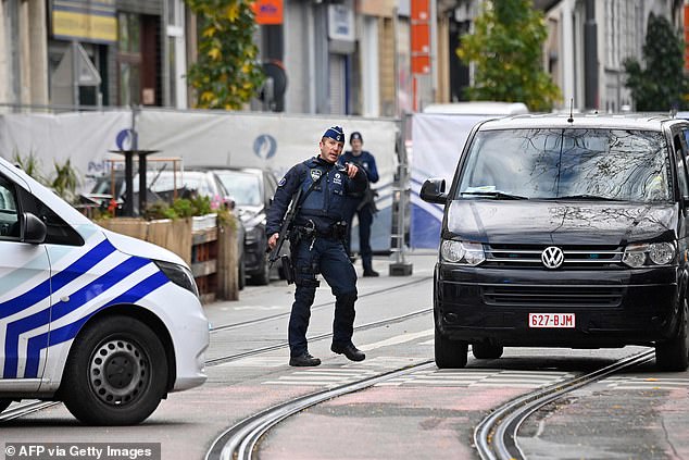 At least seven BBC News website reports about the Westminster atrocity in March 2017 which killed six people including the attacker and injured 50 people, also describe it as a 'terror attack'. Pictured: A police officer gestures as he stands guard in front of the house in the Schaerbeek area of Brussels