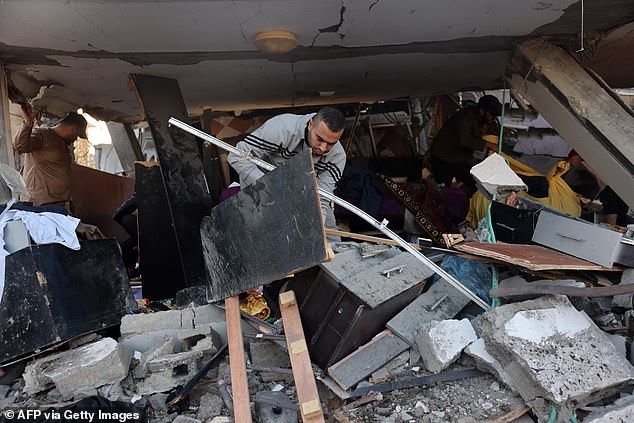A man salvages objects amid the rubble of a school hit during an Israeli strike on the Gaza Strip