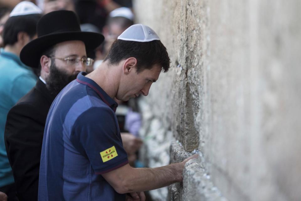 spanFC Barcelona football player Lionel Messi (R) puts a paper with wishes in a crack in the Western Wall, Judaism's holiest site, in Jerusalem on August 4, 2013/spandivspanOLIVER WEIKEN/spanspanPOOL/span/div