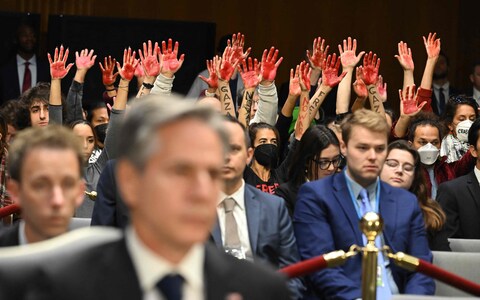 Code Pink protesters raise their painted hands as US Secretary of State Antony Blinken and Defense Secretary Lloyd Austin prepare to testify during a Senate Appropriations Committee hearing